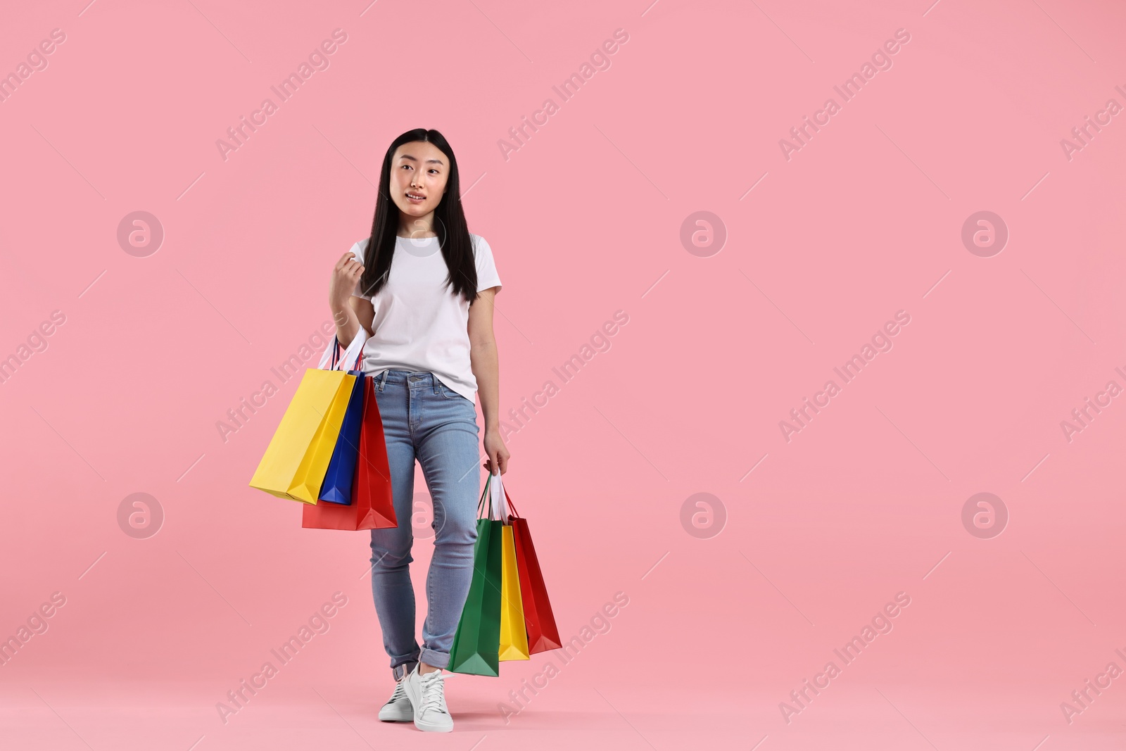 Photo of Beautiful woman with shopping bags on pink background. Space for text