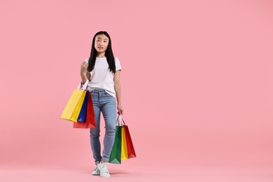 Beautiful woman with shopping bags on pink background. Space for text