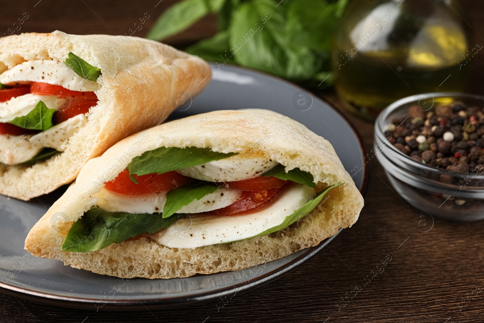 Photo of Delicious pita sandwiches with mozzarella, tomatoes and basil on wooden table, closeup