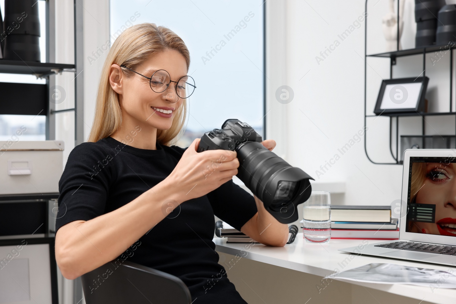 Photo of Professional photographer with digital camera at table in office