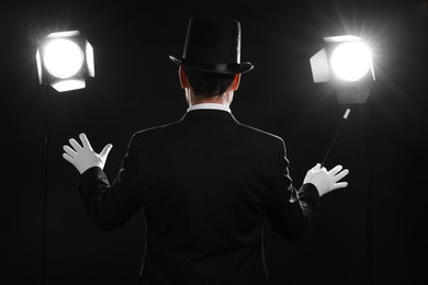 Magician with wand on stage, back view