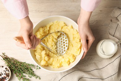 Photo of Woman making mashed potato at wooden table, top view