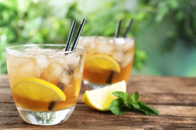 Photo of Delicious iced tea on wooden table outdoors