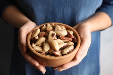 Woman holding bowl with Brazil nuts, closeup