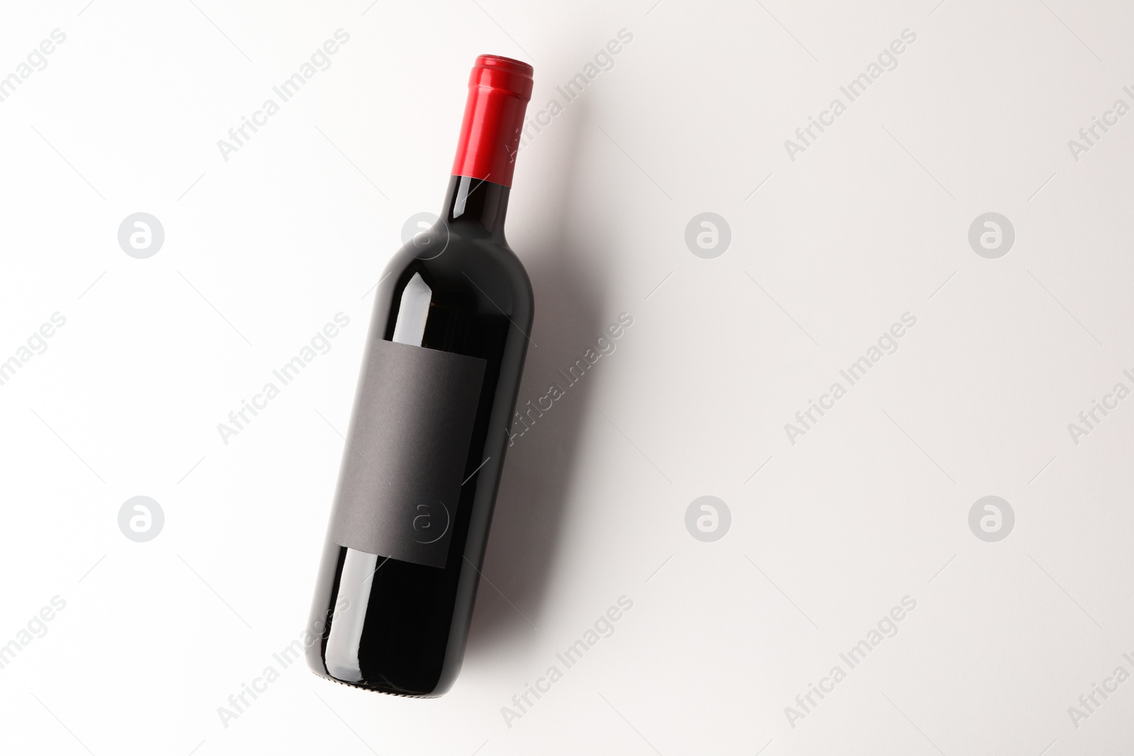 Photo of Bottle of tasty red wine on white background, top view. Space for text