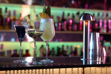 Photo of Different fresh alcoholic cocktails on counter in bar. Space for text