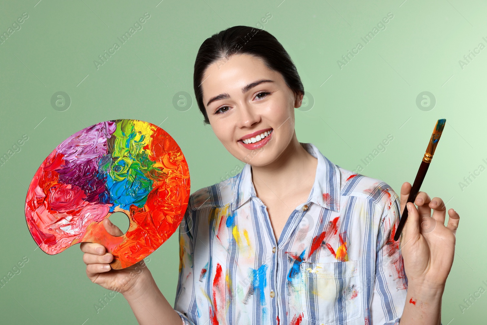 Photo of Woman with painting tools on pale green background. Young artist