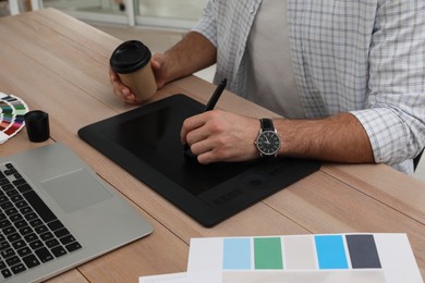 Professional designer with graphic tablet at wooden table, closeup