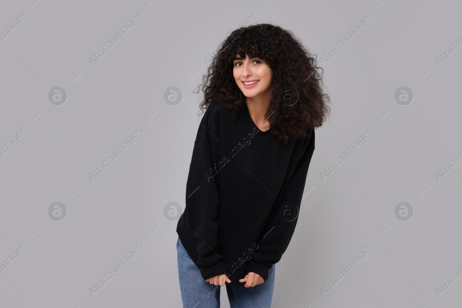 Photo of Happy young woman in stylish black sweater on light grey background