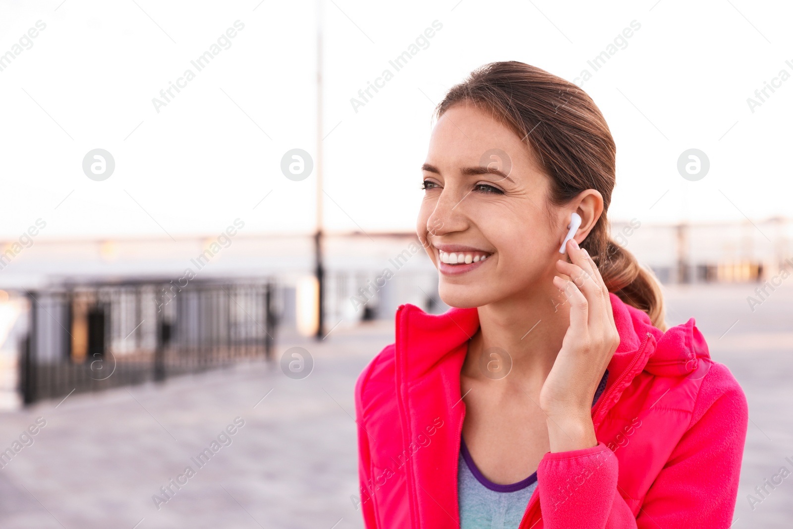 Photo of Young woman with wireless headphones listening to music outdoors. Space for text