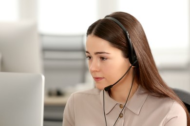 Photo of Hotline operator with headset working on computer in office