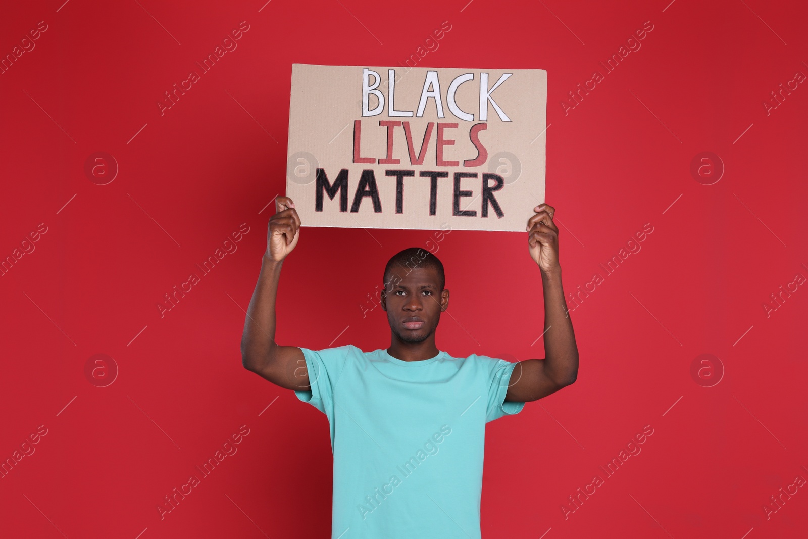 Photo of African American man holding sign with phrase Black Lives Matter on red background. End racism