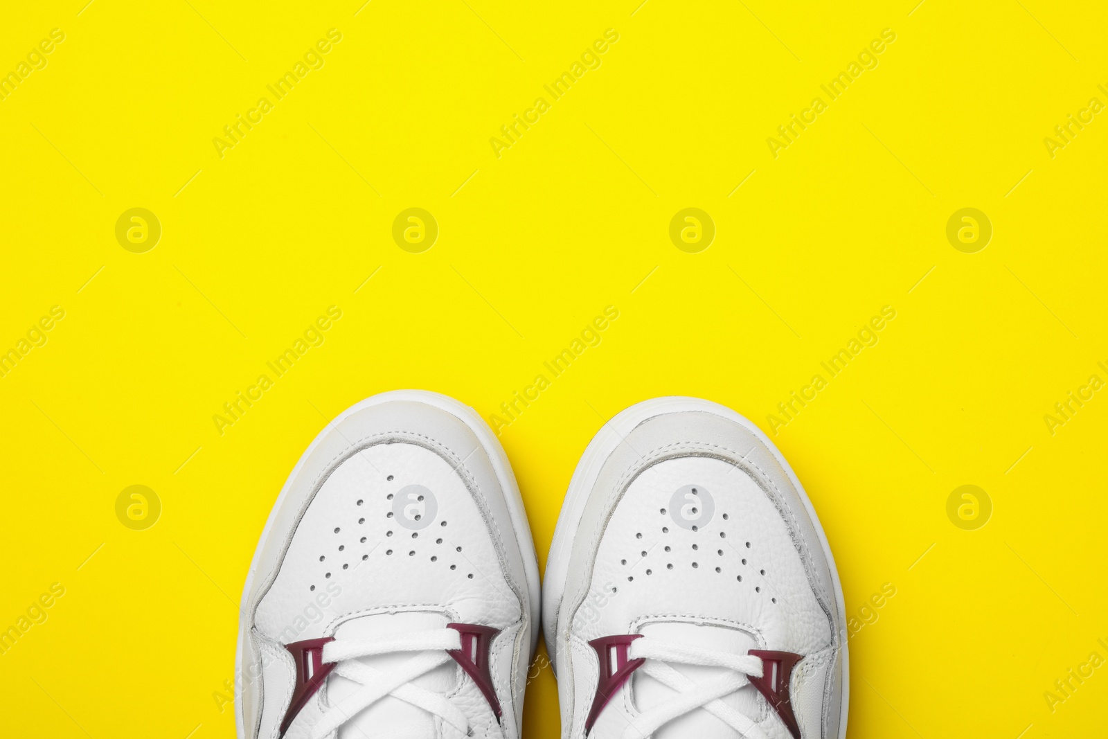 Photo of Pair of stylish shoes on yellow background, top view. Space for text