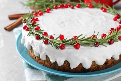 Photo of Traditional Christmas cake decorated with rosemary and cranberries on light grey marble table, closeup