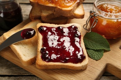 Photo of Delicious toasts with jam on wooden board, closeup