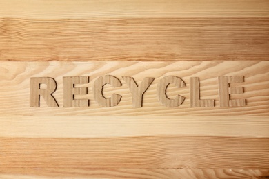 Photo of Word "Recycle" made of cardboard letters on wooden background, top view