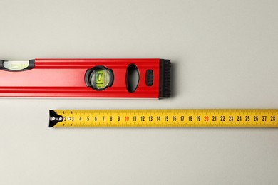 Photo of Building level and tape measure on beige background, top view