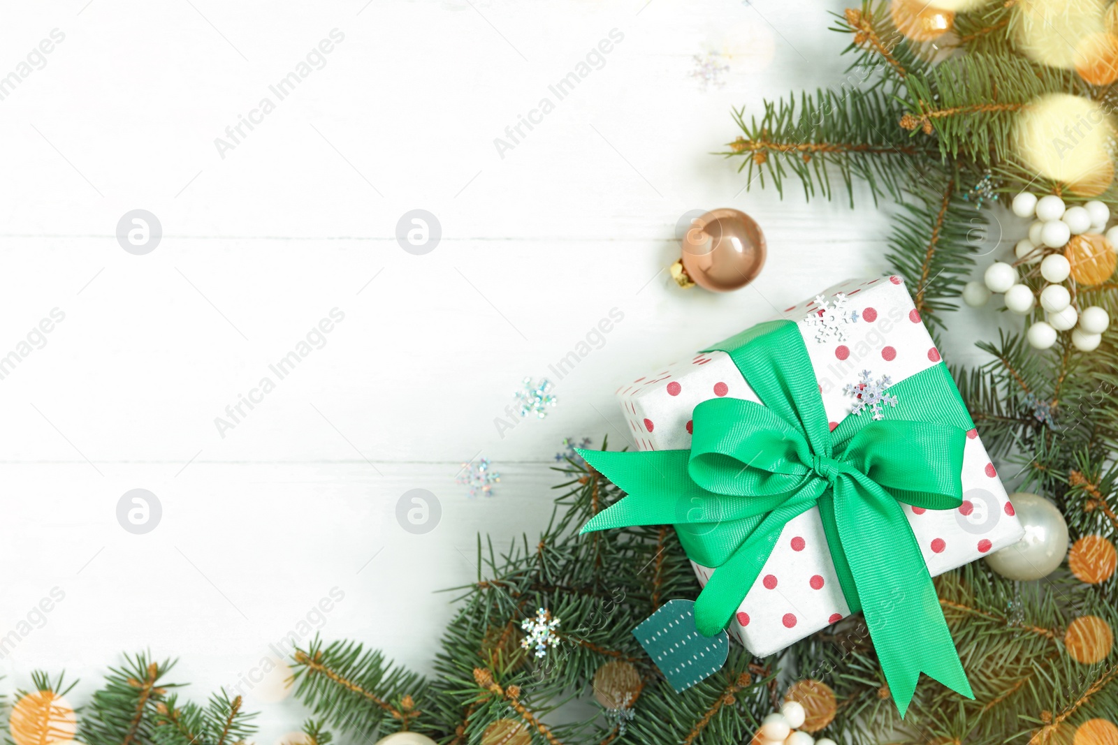 Photo of Flat lay composition with Christmas gift box and decor on white wooden table, space for text