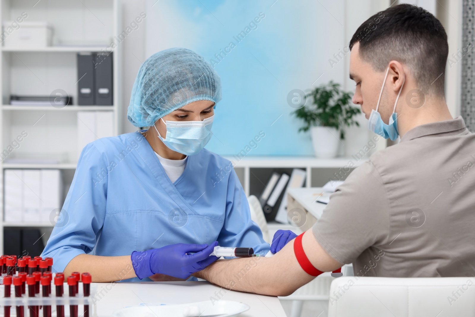 Photo of Laboratory testing. Doctor taking blood sample from patient at white table in hospital