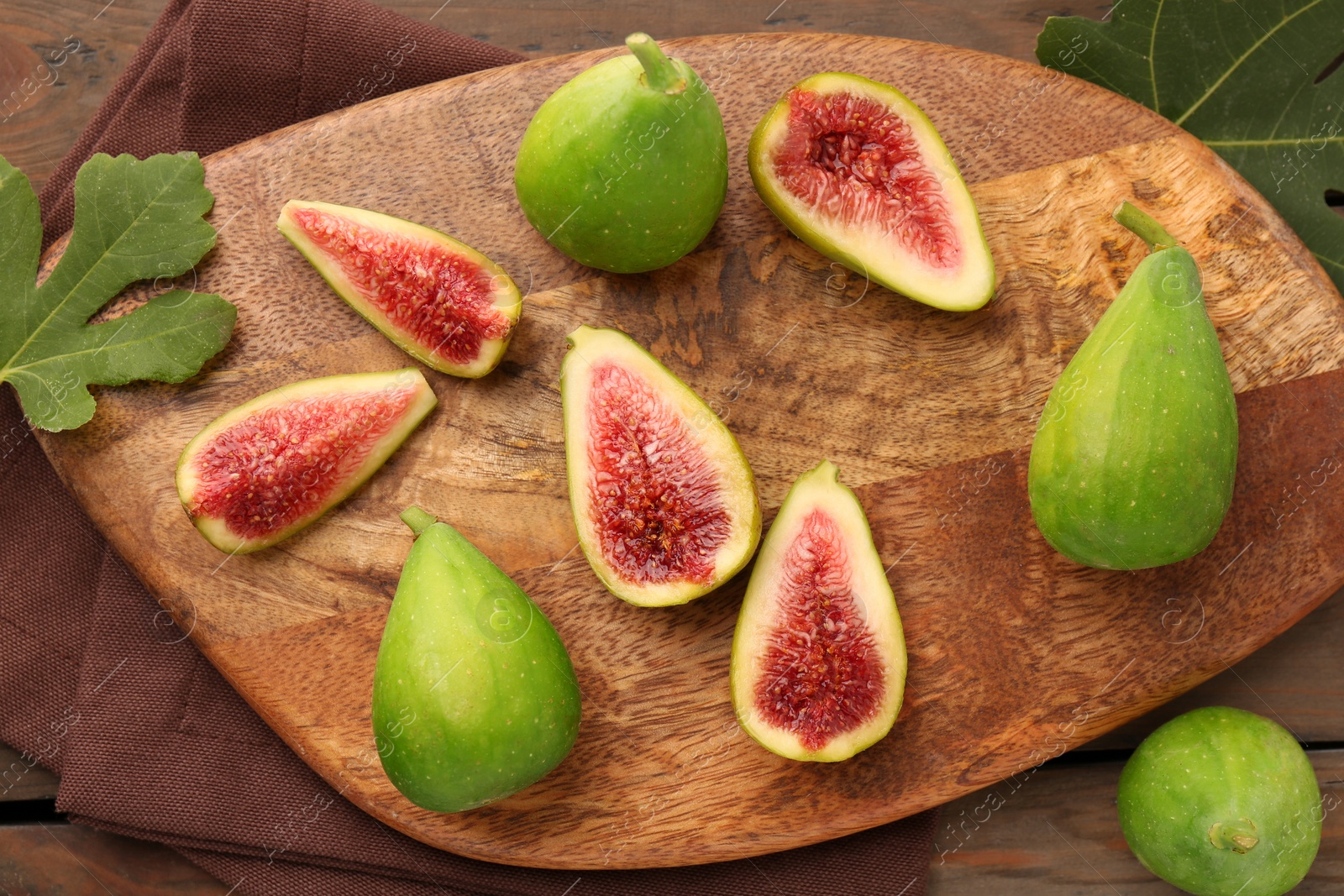 Photo of Cut and whole green figs on wooden table, flat lay