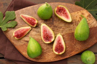 Cut and whole green figs on wooden table, flat lay