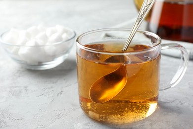 Tasty tea with sugar in cup on grey textured table, closeup