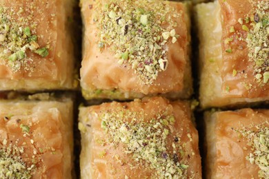 Photo of Delicious fresh baklava with chopped nuts as background, top view. Eastern sweets