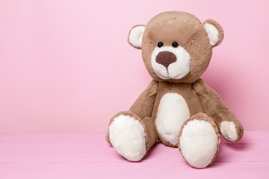 Photo of Cute teddy bear on pink background, space for text