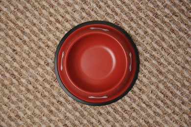 Empty red feeding bowl on soft carpet, top view