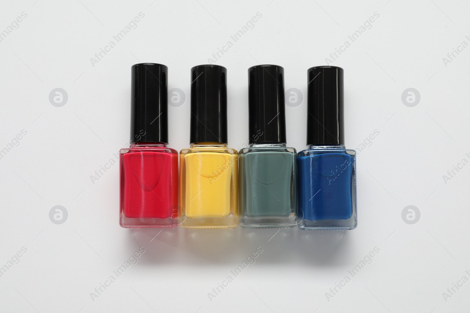 Photo of Nail polishes on white background, flat lay