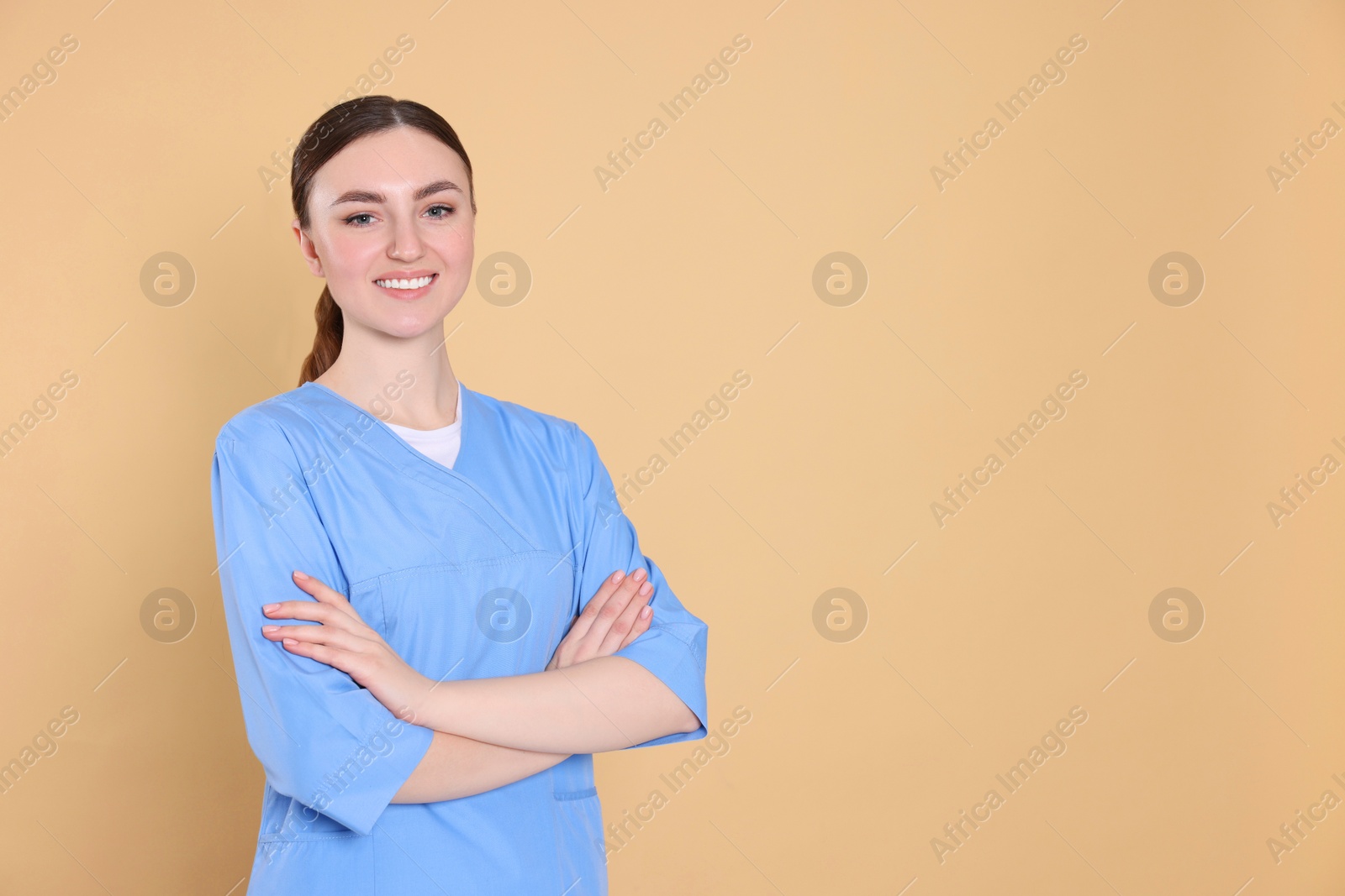 Photo of Portrait of nurse in medical uniform on light brown background, space for text