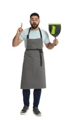 Emotional young man with brush and dustpan on white background