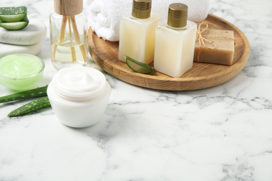 Different cosmetic products and aloe on white marble table