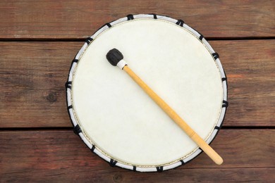 Photo of Modern drum with drumstick on wooden table, top view. Percussion musical instrument
