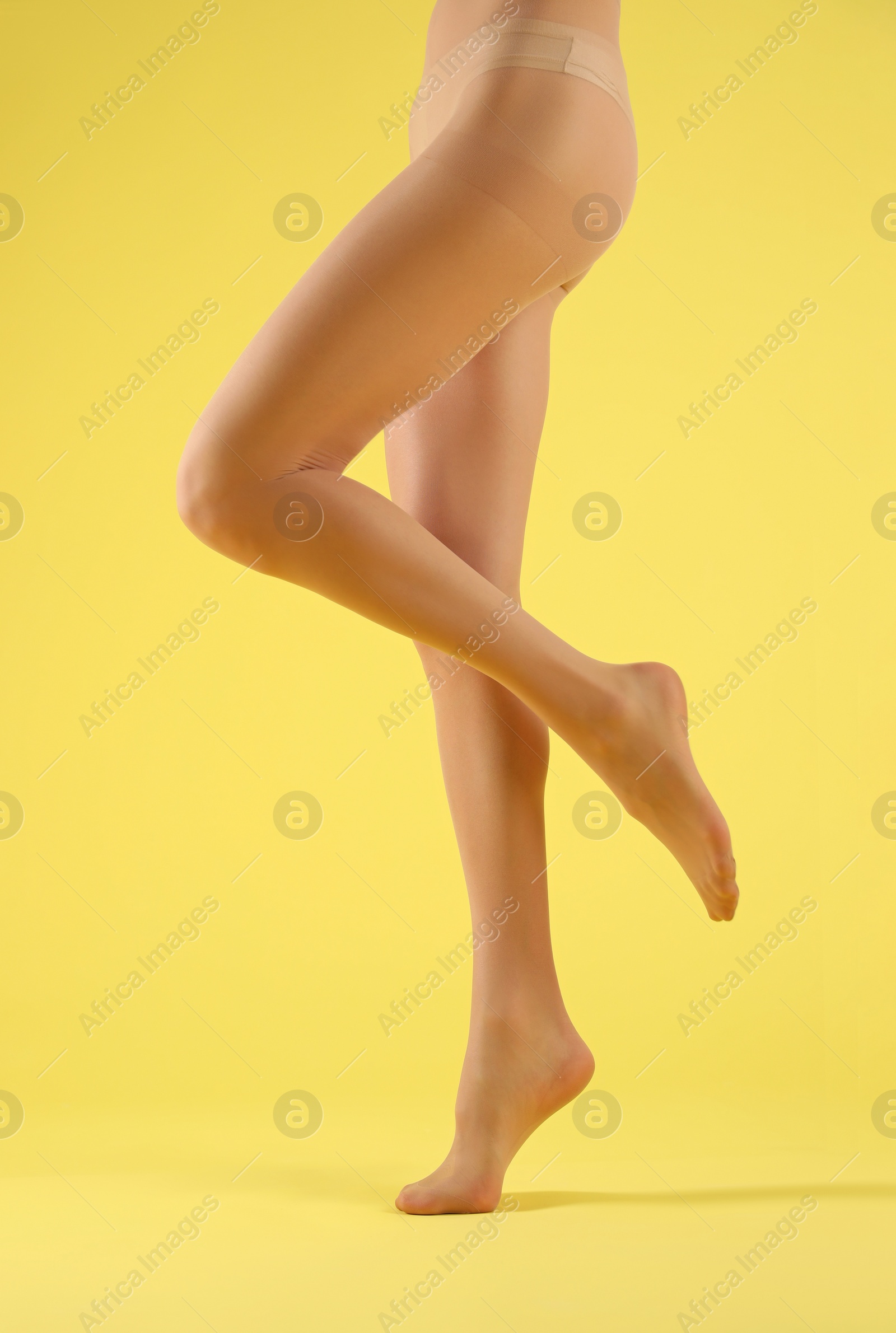 Photo of Woman wearing tights on yellow background, closeup of legs