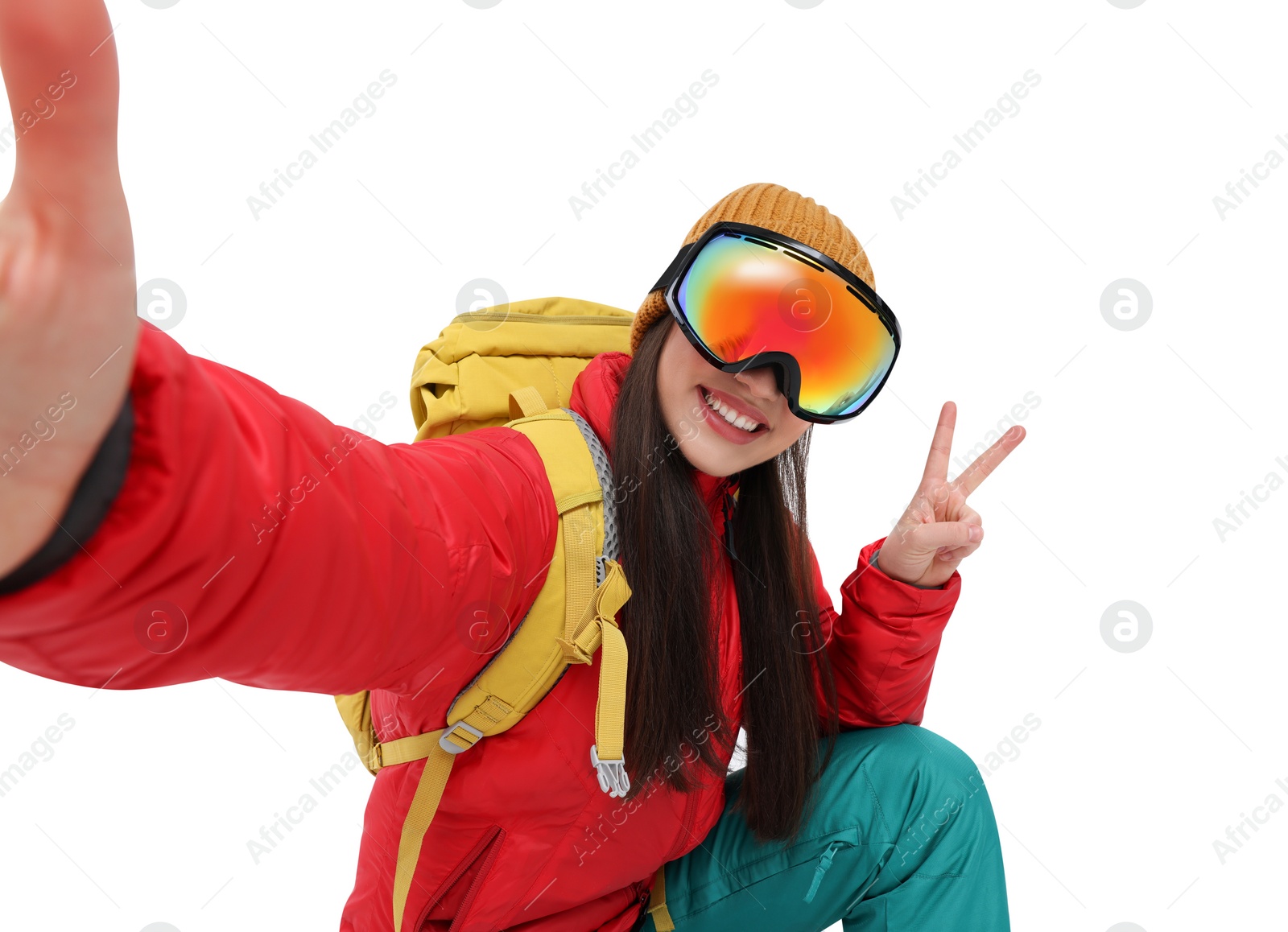 Photo of Smiling woman in ski goggles taking selfie and showing peace sign on white background