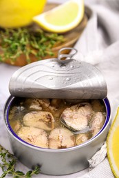 Photo of Open tin can with mackerel chunks on white marble table, closeup