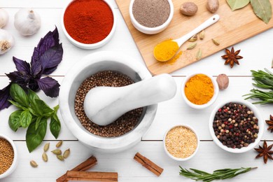 Photo of Mortar with pestle and different spices on white wooden table, flat lay