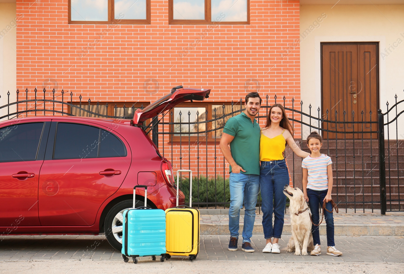 Photo of Happy family with their dog near car on street