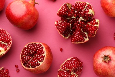 Whole and cut fresh pomegranates on pink background, flat lay