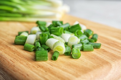 Photo of Chopped green onion on wooden board, closeup