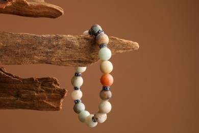Photo of Stylish presentation of beautiful bracelet with gemstones on brown background, space for text