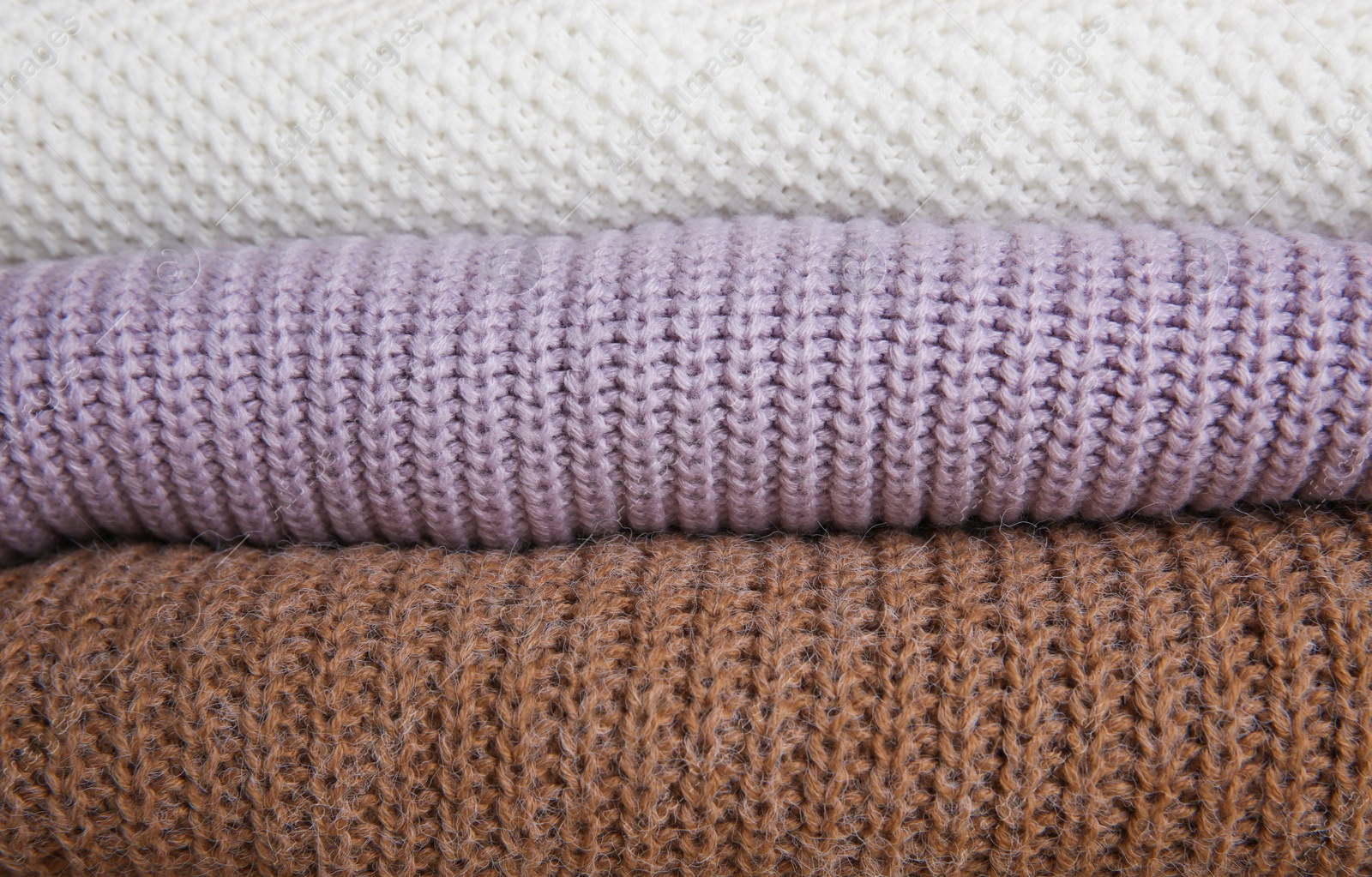 Photo of Stack of folded knitted sweaters as background, closeup