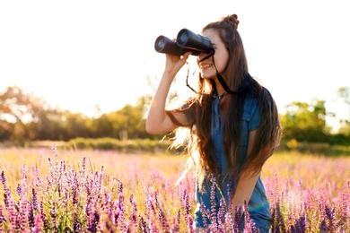 Photo of Teenage girl with binoculars in field. Summer camp