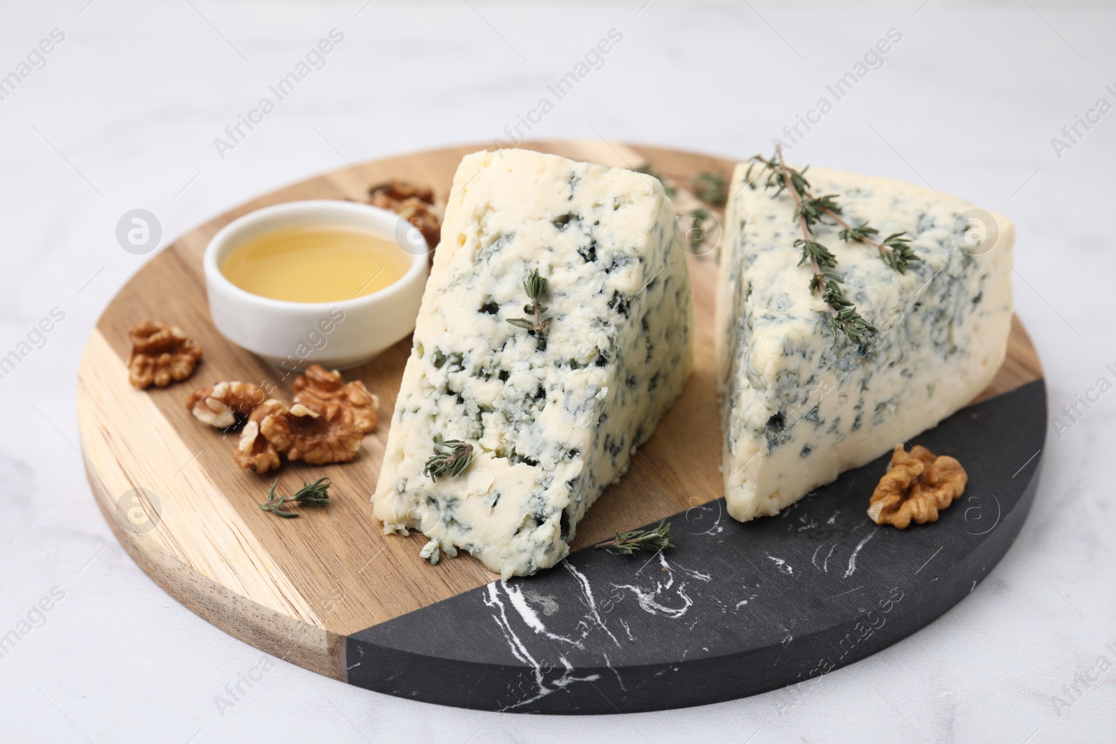 Photo of Tasty blue cheese with thyme, honey and walnuts on white marble table