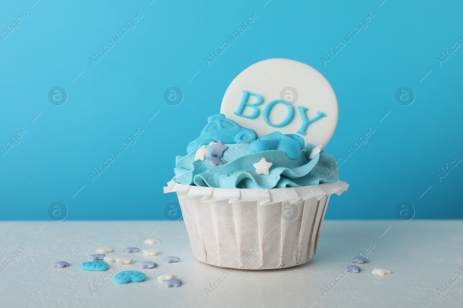 Photo of Baby shower cupcake with Boy topper on white table against light blue background