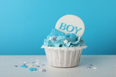 Photo of Baby shower cupcake with Boy topper on white table against light blue background