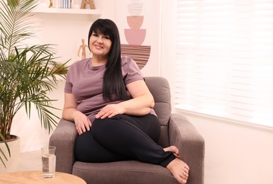 Photo of Beautiful overweight woman sitting in armchair at home