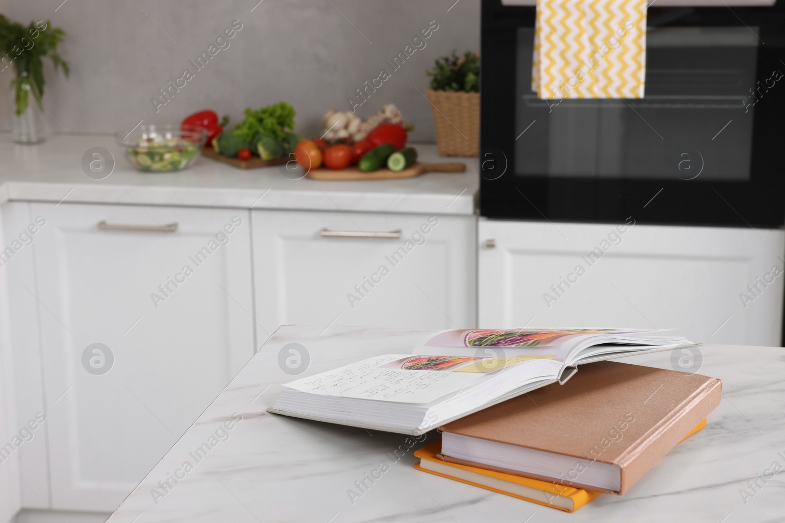 Photo of Recipe books on white marble table in kitchen, closeup. Space for text