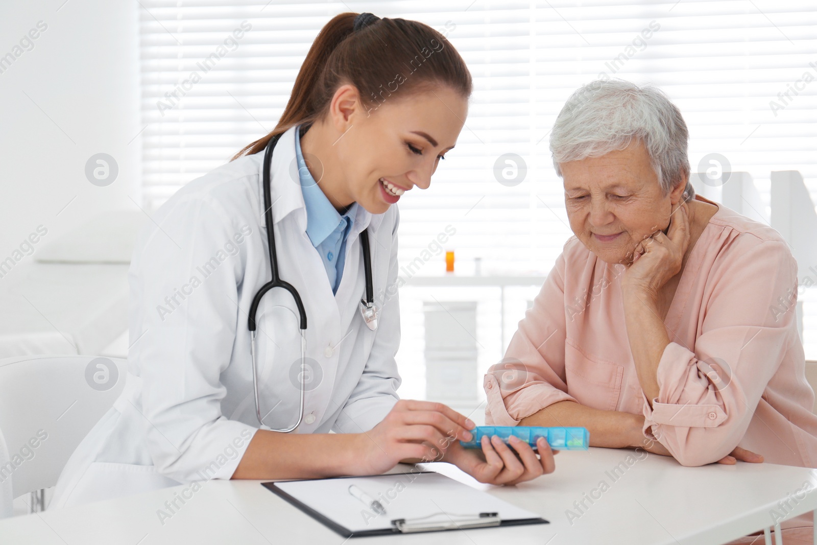 Photo of Doctor giving pills to senior patient in office